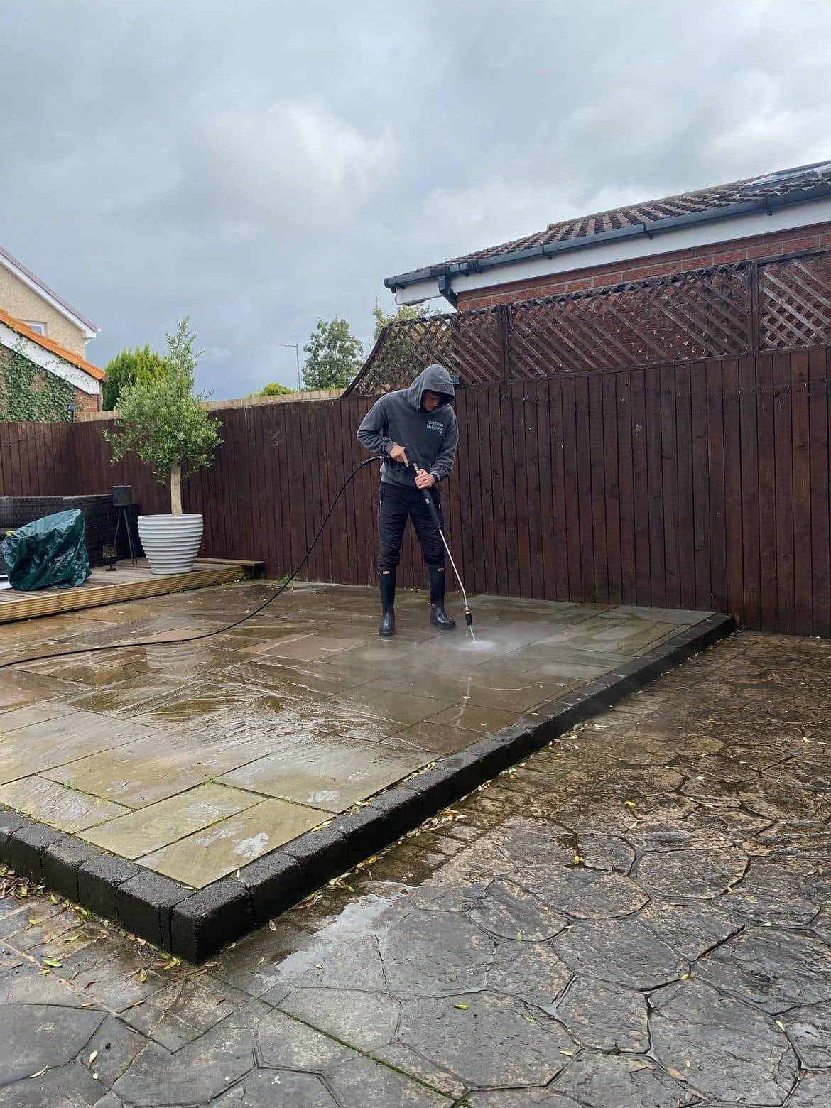 Pressure washing an Indian sandstone patio in a back garden
