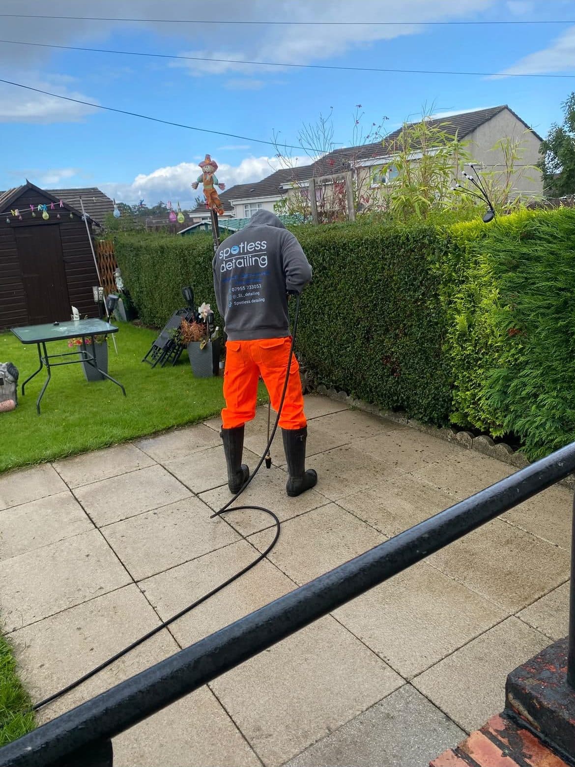Pressure washing concrete patio slabs in a back garden