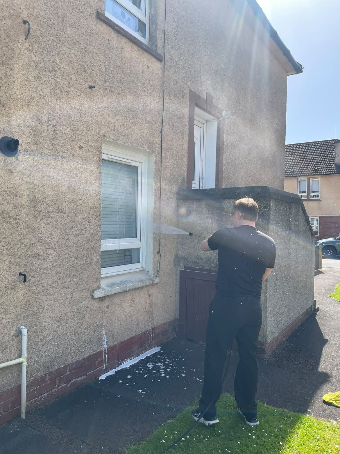 Soft washing a roughcast render wall on a house
