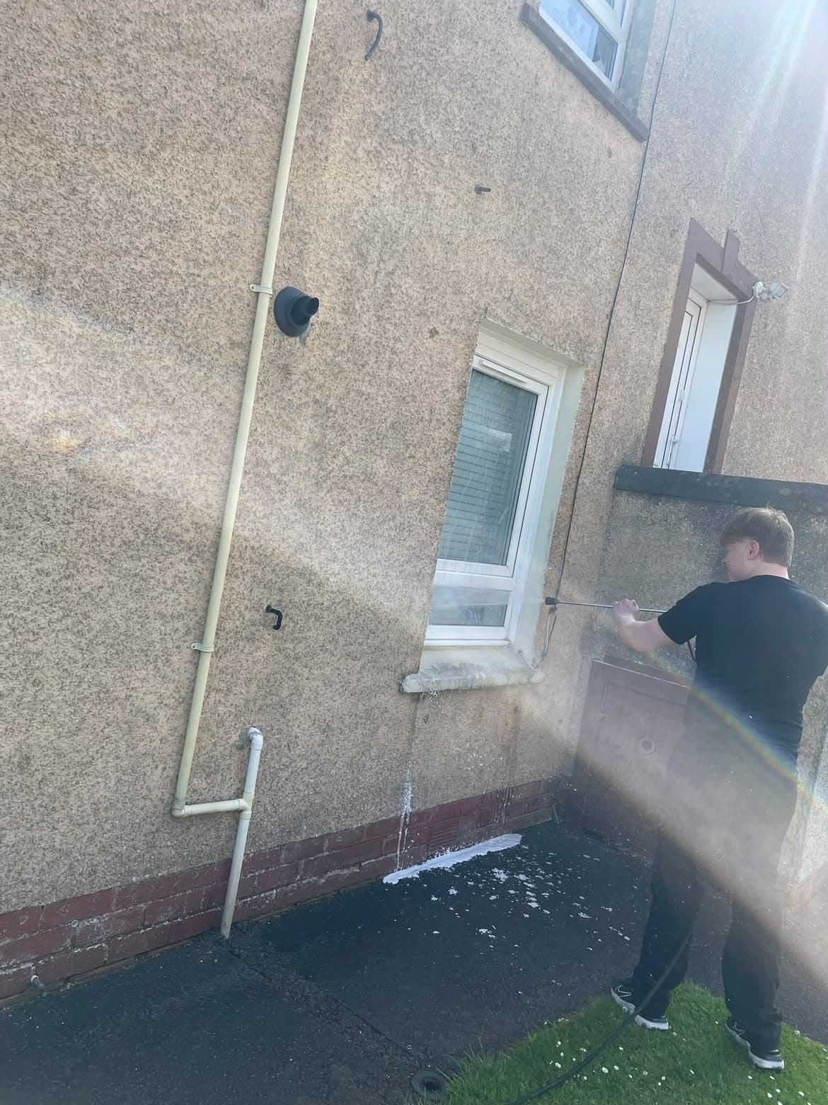 Rinsing roughcast render around a window and downpipe