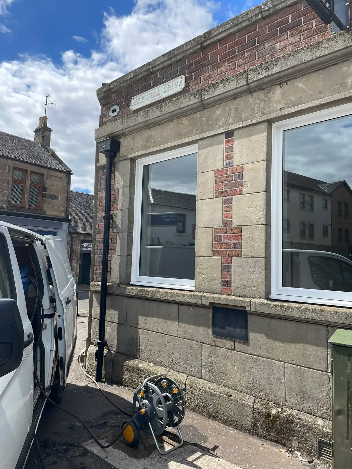 Pressure washing the stonework of a corner shopfront